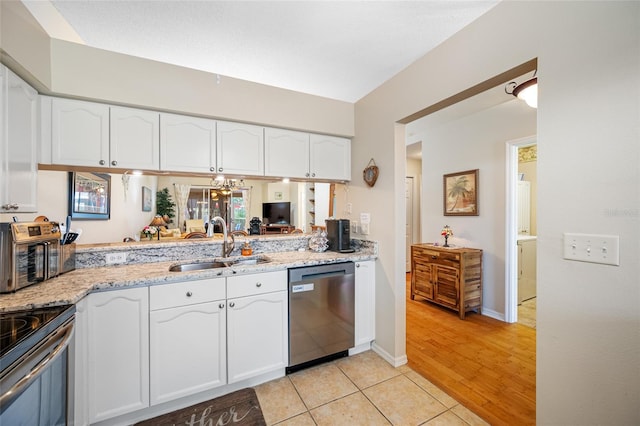 kitchen featuring sink, white cabinetry, light tile patterned floors, appliances with stainless steel finishes, and light stone countertops