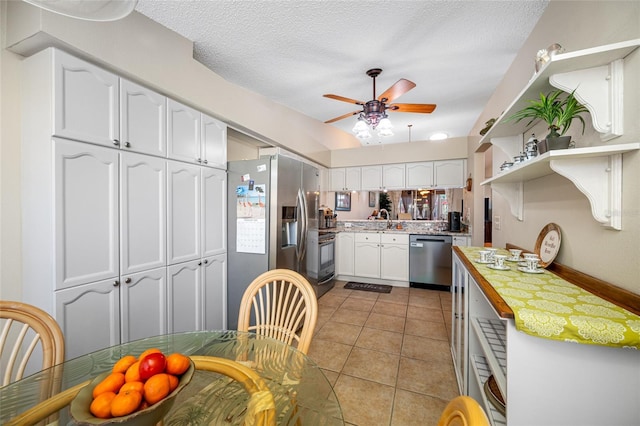 kitchen featuring light tile patterned flooring, tile countertops, white cabinetry, ceiling fan, and stainless steel appliances