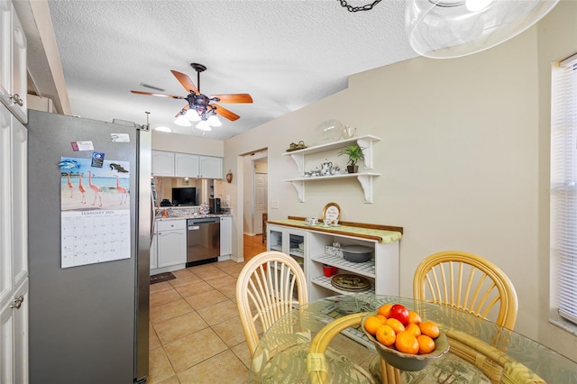 kitchen with stainless steel appliances, white cabinetry, light tile patterned floors, and ceiling fan