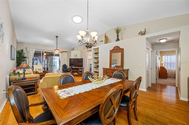 dining space with built in features, a notable chandelier, a textured ceiling, vaulted ceiling, and light wood-type flooring