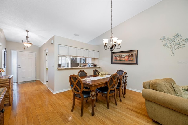 dining room with vaulted ceiling, a chandelier, and light hardwood / wood-style floors