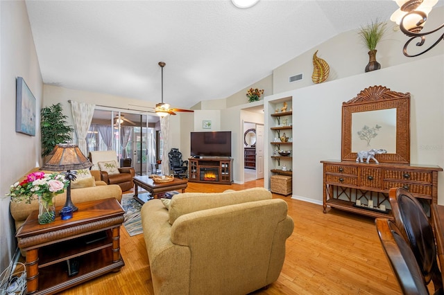 living room featuring vaulted ceiling, a textured ceiling, and light hardwood / wood-style floors