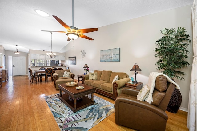 living room with ceiling fan with notable chandelier, vaulted ceiling, light hardwood / wood-style floors, and a textured ceiling