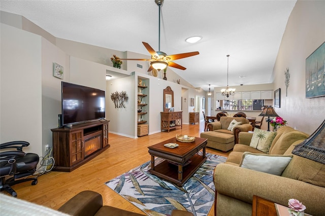 living room featuring lofted ceiling, ceiling fan with notable chandelier, a textured ceiling, and light wood-type flooring