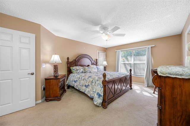 bedroom with ceiling fan, light colored carpet, and a textured ceiling