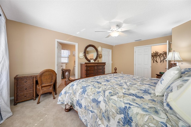 carpeted bedroom featuring ceiling fan, connected bathroom, a closet, and a textured ceiling