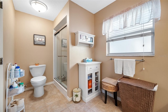 bathroom featuring a shower with door, tile patterned flooring, and toilet