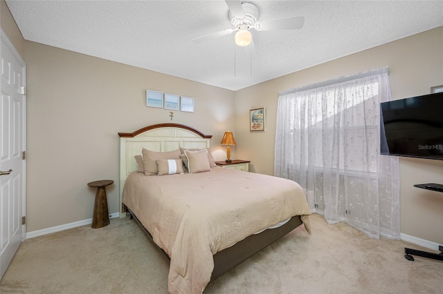 bedroom with ceiling fan, light carpet, and a textured ceiling