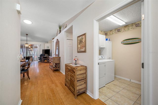 laundry room with cabinets, a textured ceiling, light hardwood / wood-style flooring, ceiling fan, and washer and clothes dryer