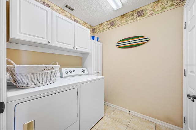 washroom with cabinets, light tile patterned floors, a textured ceiling, and washer and clothes dryer