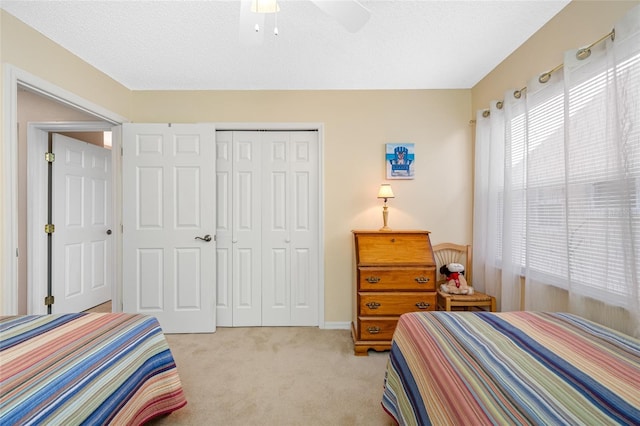 bedroom with ceiling fan, light carpet, a textured ceiling, and a closet