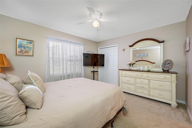 bedroom with ceiling fan, light colored carpet, a textured ceiling, and a closet