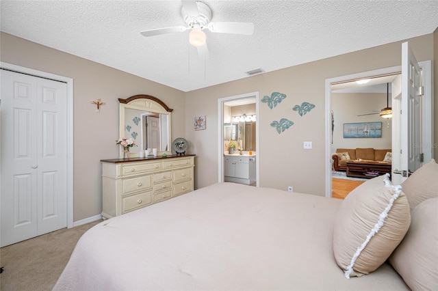 carpeted bedroom with connected bathroom, ceiling fan, a closet, and a textured ceiling