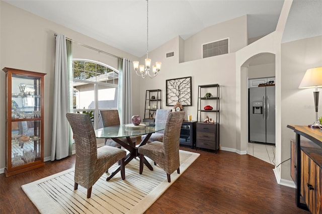 dining space with a notable chandelier, dark wood-type flooring, and vaulted ceiling