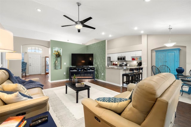 living room featuring ceiling fan, lofted ceiling, sink, and wood-type flooring