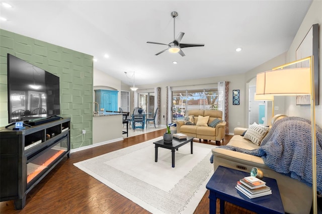 living room featuring lofted ceiling, dark wood-type flooring, and ceiling fan