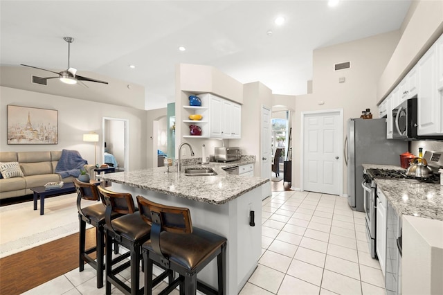 kitchen with stainless steel appliances, white cabinetry, sink, and a kitchen bar