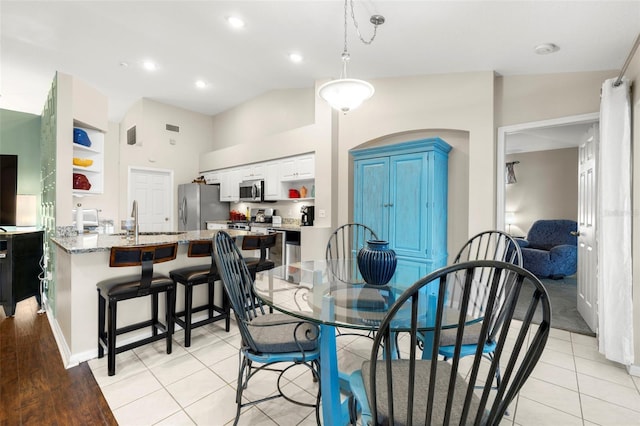 dining space with lofted ceiling, sink, and light tile patterned floors