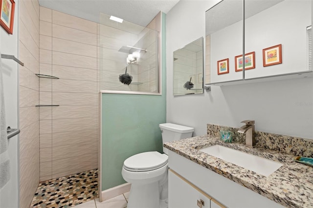 bathroom featuring vanity, toilet, and a tile shower