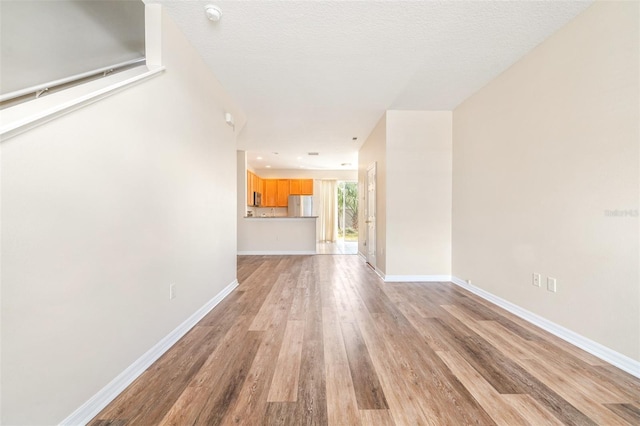 unfurnished living room with light hardwood / wood-style flooring and a textured ceiling