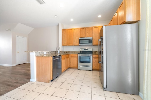 kitchen with light stone counters, stainless steel appliances, kitchen peninsula, and light tile patterned floors