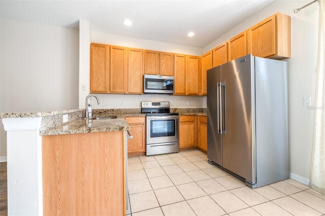 kitchen with sink, light stone counters, light tile patterned floors, appliances with stainless steel finishes, and kitchen peninsula