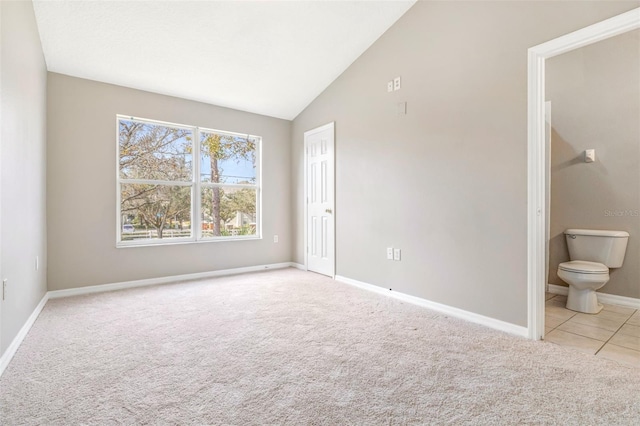 interior space with connected bathroom, light colored carpet, and high vaulted ceiling