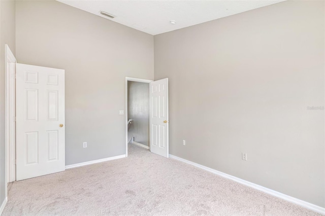 unfurnished room featuring light carpet and a high ceiling