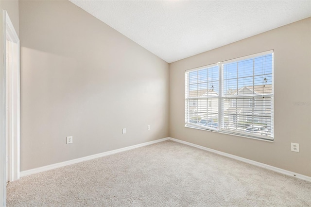 empty room with vaulted ceiling, carpet flooring, and a textured ceiling