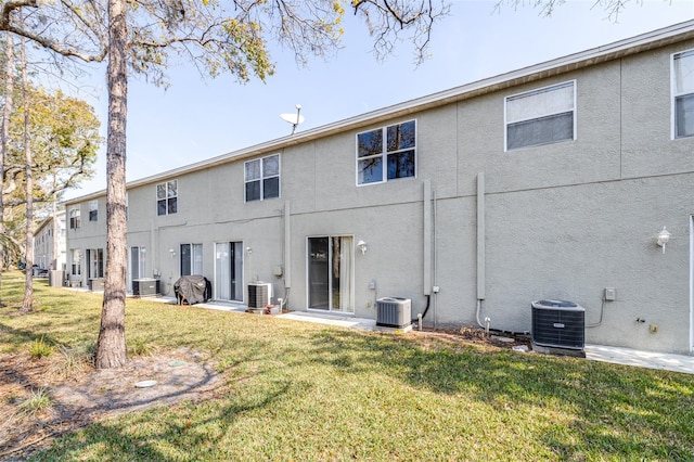 rear view of house with central AC and a yard