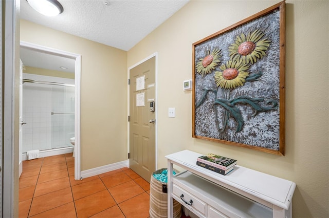 hall with a textured ceiling and light tile patterned floors