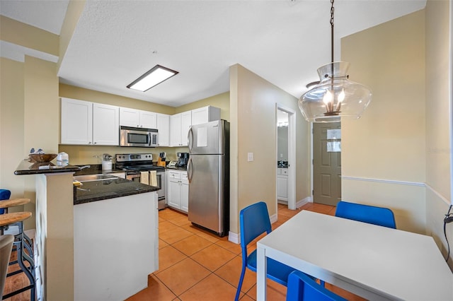 kitchen featuring pendant lighting, light tile patterned floors, appliances with stainless steel finishes, white cabinets, and kitchen peninsula