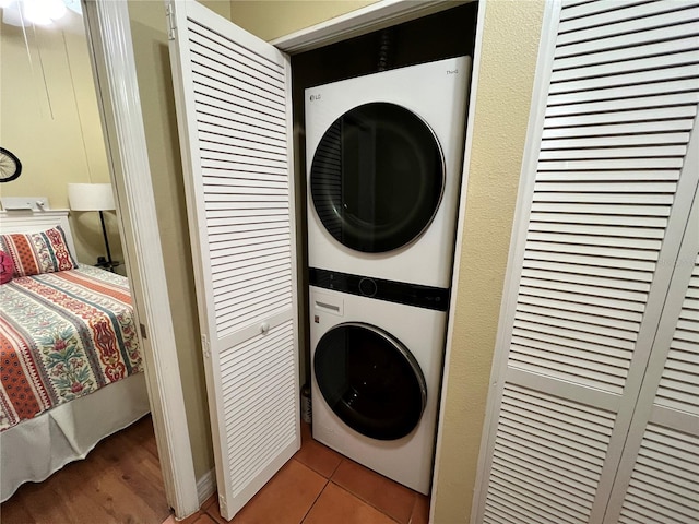 clothes washing area featuring light tile patterned flooring and stacked washer and dryer