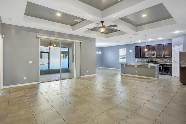 kitchen with decorative light fixtures, ceiling fan, stainless steel appliances, a kitchen island with sink, and backsplash