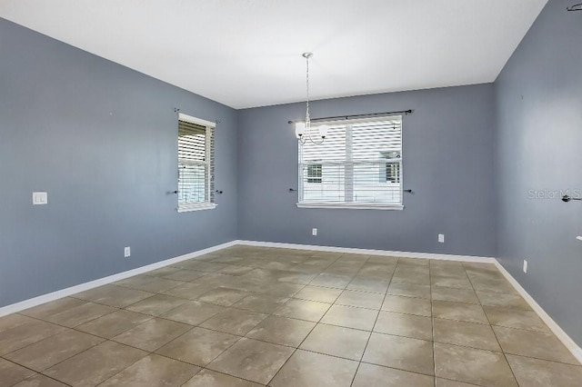 empty room with an inviting chandelier and light tile patterned flooring