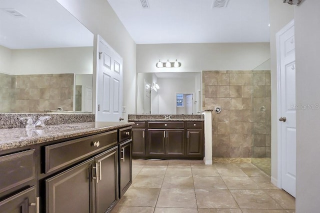 bathroom with walk in shower, vanity, and tile patterned flooring