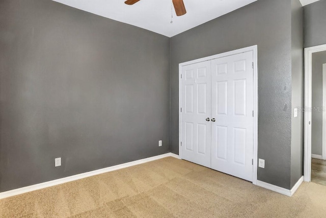 unfurnished bedroom featuring ceiling fan, light colored carpet, and a closet