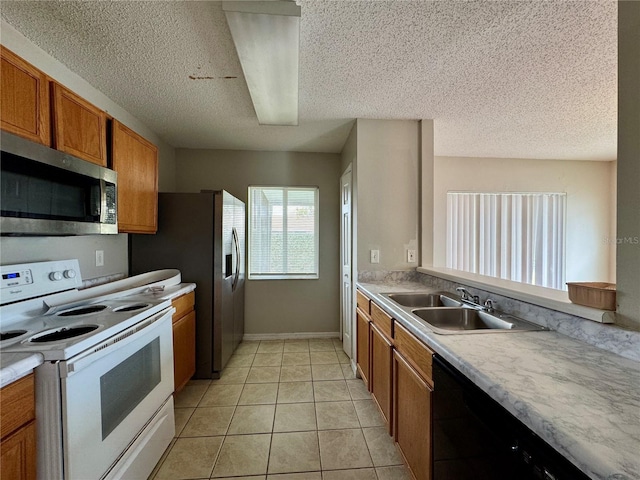 kitchen featuring electric stove, sink, light tile patterned floors, dishwasher, and a textured ceiling