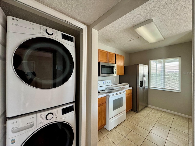 kitchen featuring stacked washer and dryer, appliances with stainless steel finishes, light tile patterned floors, and a textured ceiling