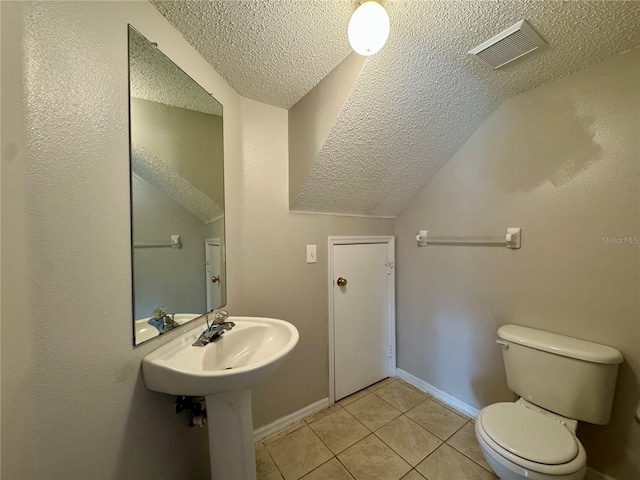 bathroom featuring tile patterned floors, toilet, vaulted ceiling, and a textured ceiling