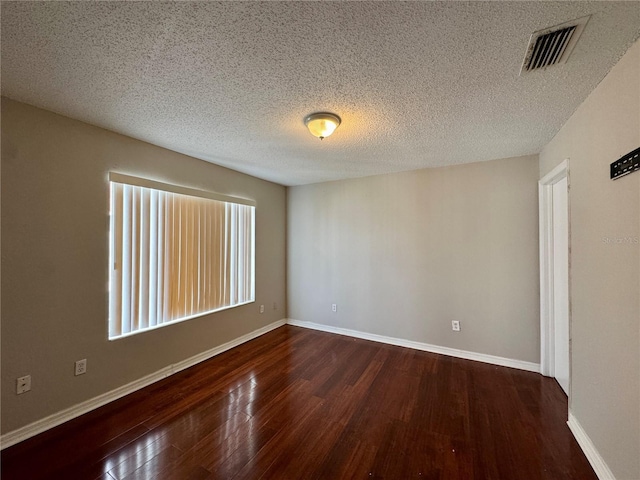 empty room featuring a textured ceiling, dark wood-type flooring, and a healthy amount of sunlight