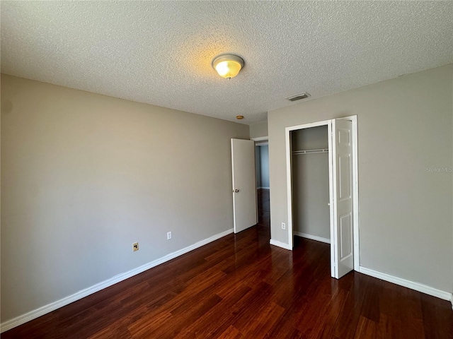 unfurnished bedroom with dark wood-type flooring, a textured ceiling, and a closet