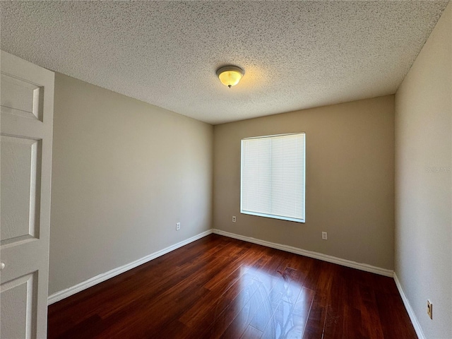 empty room with dark hardwood / wood-style floors and a textured ceiling