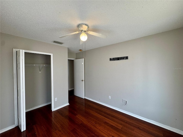 unfurnished bedroom featuring a closet, dark hardwood / wood-style floors, a textured ceiling, and ceiling fan