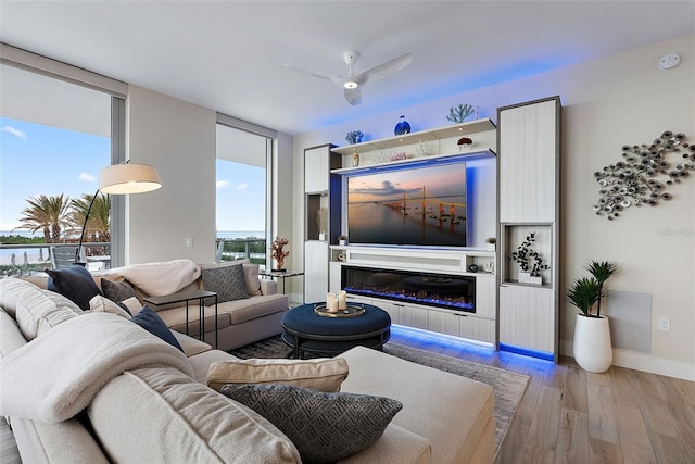 living room with ceiling fan, floor to ceiling windows, and light hardwood / wood-style flooring