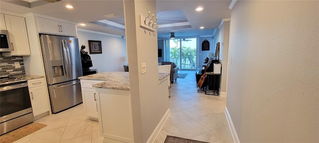 kitchen featuring appliances with stainless steel finishes, tasteful backsplash, white cabinetry, ornamental molding, and light stone countertops