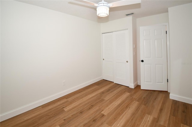 unfurnished bedroom with hardwood / wood-style flooring, ceiling fan, and a closet