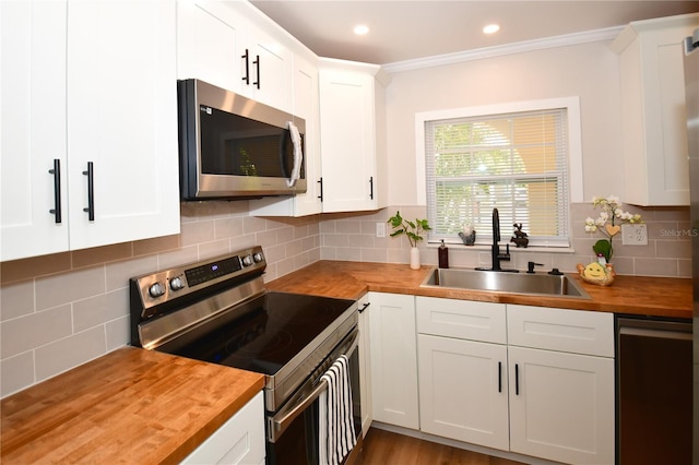 kitchen with white cabinetry, appliances with stainless steel finishes, sink, and butcher block countertops