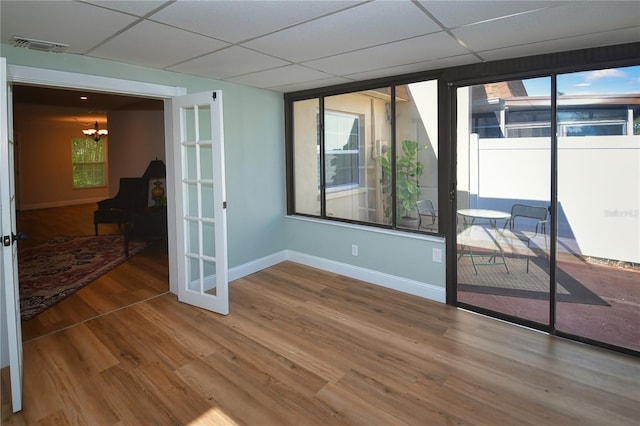 empty room with hardwood / wood-style floors, a drop ceiling, and french doors