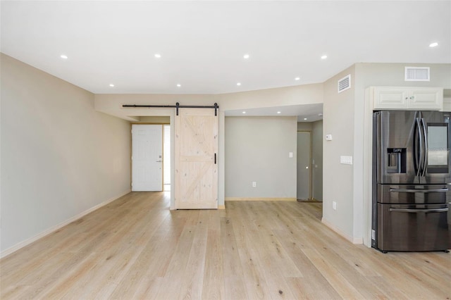 interior space with light hardwood / wood-style flooring, a barn door, white cabinets, and stainless steel refrigerator with ice dispenser